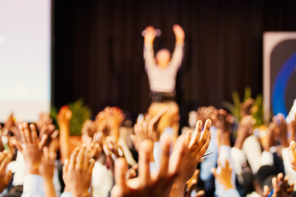 Professionals raising their hands at an industry conference.